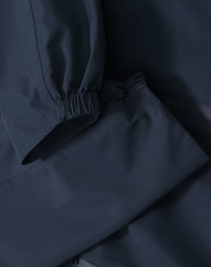 A waterproof jacket in navy blue with elastic cuffs and a sleek design, featuring a logo.