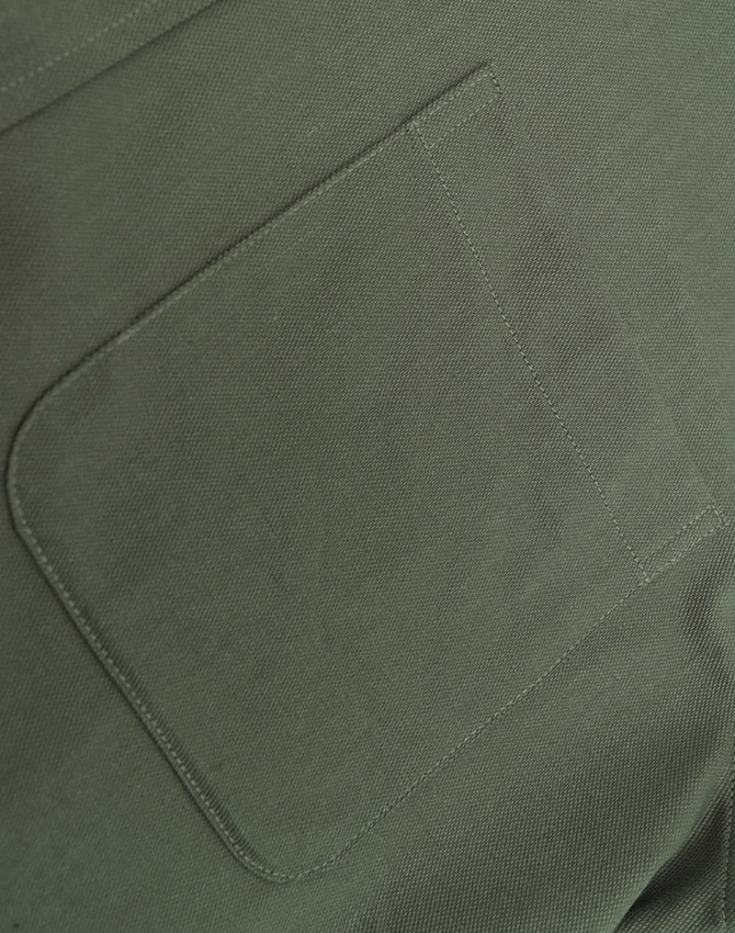 A close-up of a green cotton blend fabric featuring a stitched pocket.