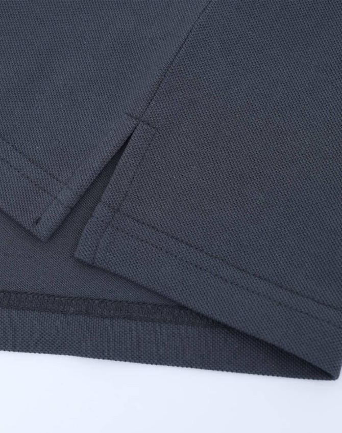 A close-up of a dark grey cotton/poly pique polo shirt, featuring seams and a small side split.