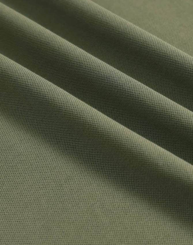 A close-up of soft, textured fabric in an olive green shade, showcasing its fine pique weave.