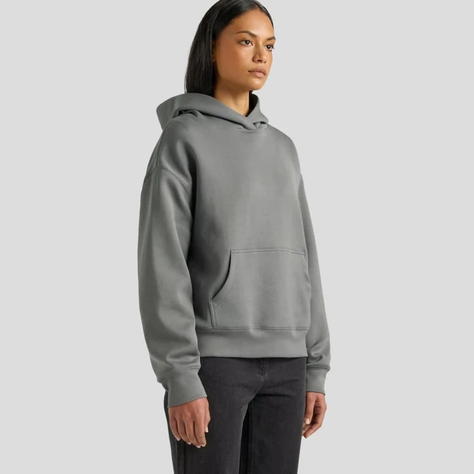 A grey hooded sweatshirt with a front pocket, featuring a relaxed fit. The model stands against a plain background.