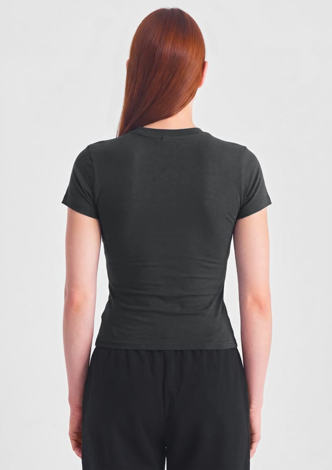 A black women's baby tee featuring a fitted design, view from the back, paired with black pants.