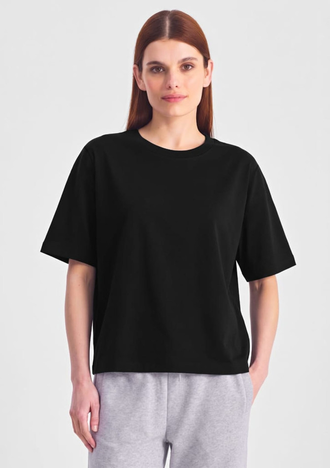 A black box tee in a relaxed fit, featuring short sleeves. The model wears it with grey bottoms.