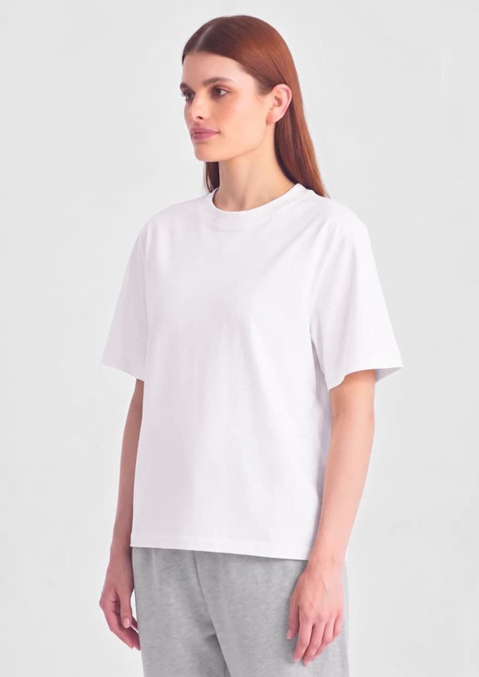 A white box tee is displayed on a model, featuring short sleeves and a relaxed fit.