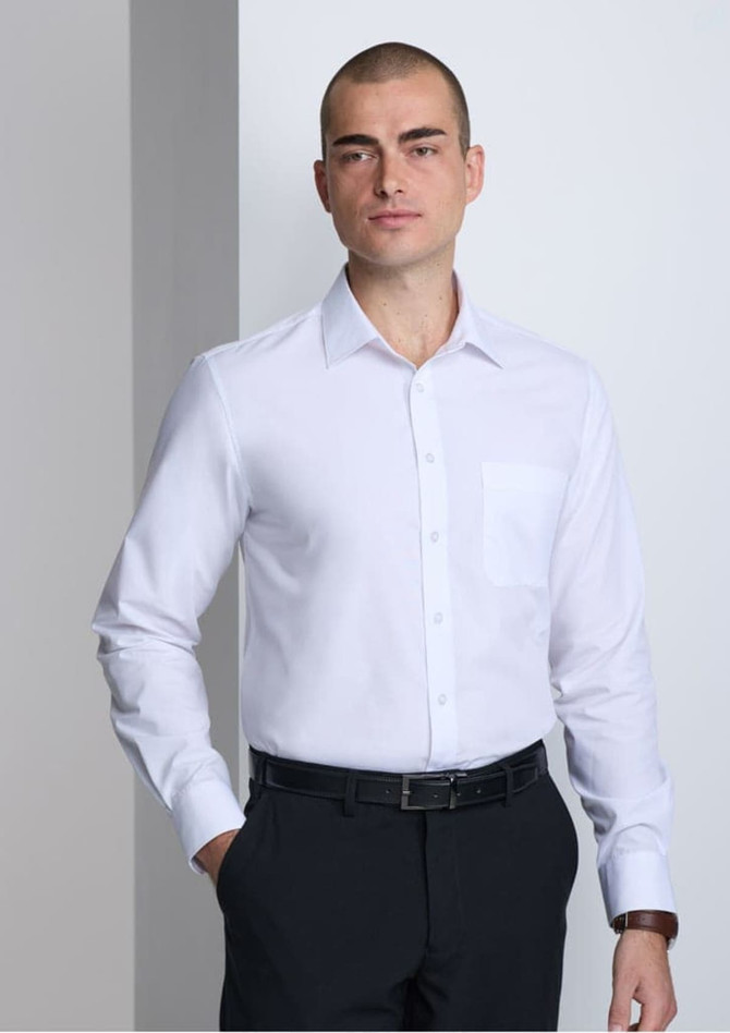 A man models a classic fit long sleeve shirt in white, featuring a pocket and a brand logo.
