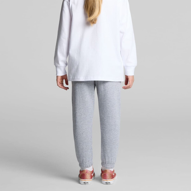 Grey track pants worn by a child, paired with a white long-sleeve top and sparkly shoes. It features a logo.