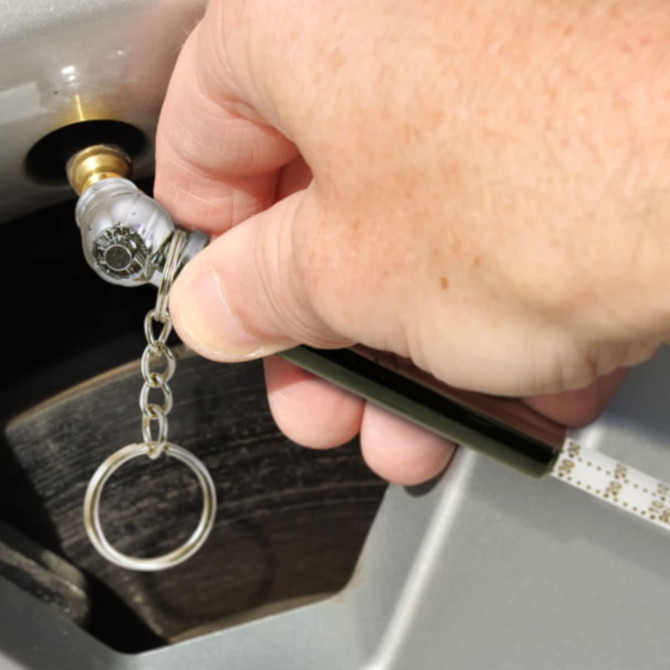 A tyre pressure gauge key ring in use, featuring a silver gauge attached to a shiny key ring.