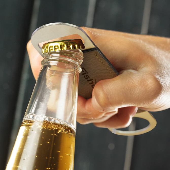 A drink bottle opener with a metallic finish, gripping the cap of a glass bottle filled with golden liquid.