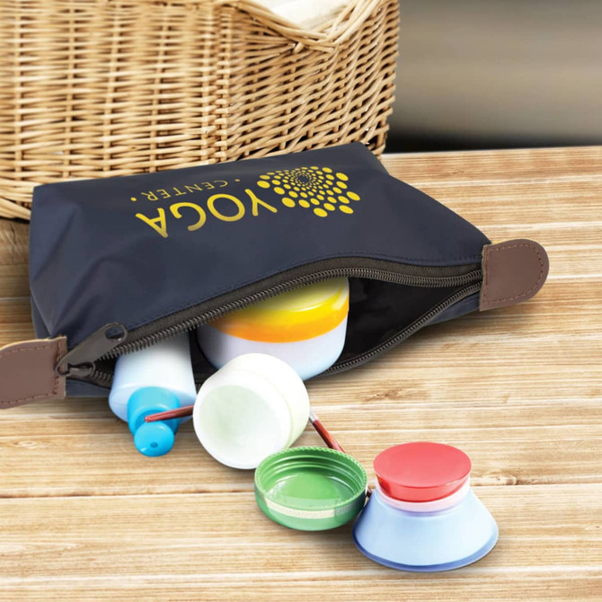A dark navy toiletry bag with various coloured containers and a logo, placed on a wooden surface.