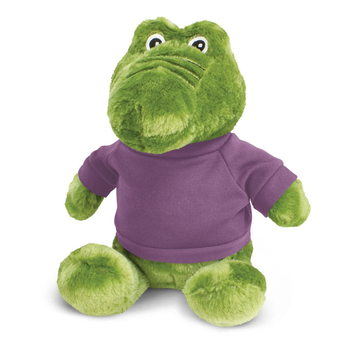 A green crocodile plush toy wearing a purple shirt, featuring large eyes and a friendly expression.
