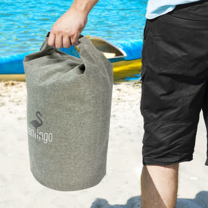 A grey 10L dry bag being held by a person on a beach near water, featuring a logo.