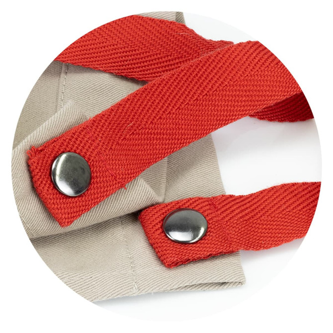 A close-up of the straps of a beige apron, featuring red adjustable straps with metal fasteners.