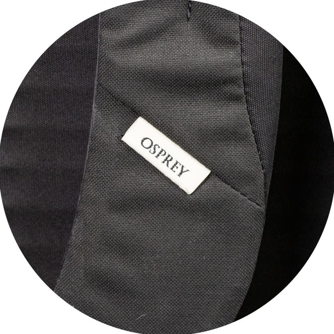 A close-up of a black fabric section featuring a small Osprey logo tag.
