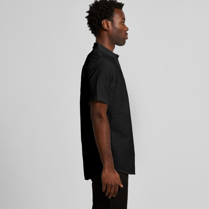 A black short-sleeve button-up shirt with a collar, featured on a model from the side. It has a logo.