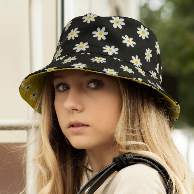 A reversible bucket hat featuring a black floral design with daisies and a contrasting yellow interior.