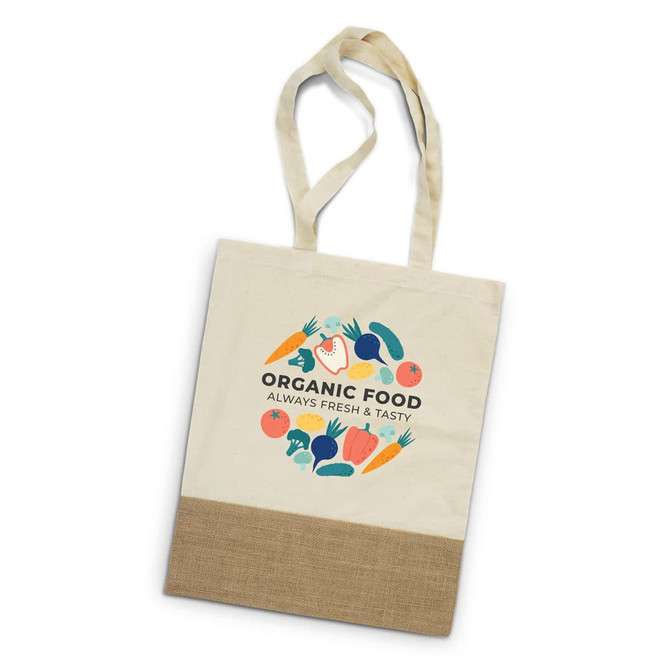 A beige tote bag with a graphic design featuring vegetables and a logo. The bottom has a natural jute texture.