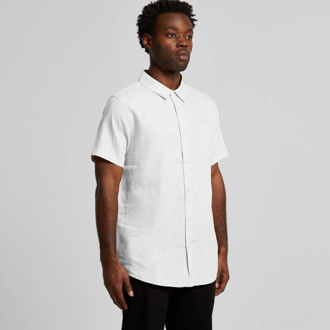 A short-sleeve button-up shirt in white, featuring a front pocket and a collar. The model stands against a plain background.