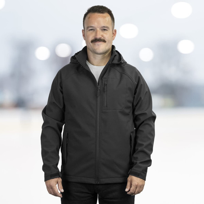 A man models a black soft shell jacket featuring a hood and zipper pockets, set against a blurred background.