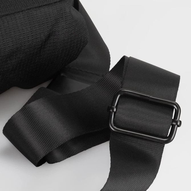 A black sling bag featuring sturdy straps and a metal buckle, showcasing a textured fabric.