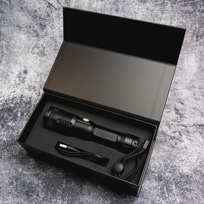 A rechargeable torch in a sleek black box, accompanied by a charging cable and a lanyard.