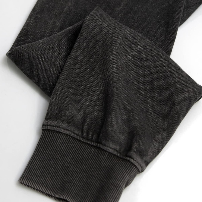 A faded black unisex hoodie showing the detail of the cuffs and sleeves, featuring a subtle texture and a logo.