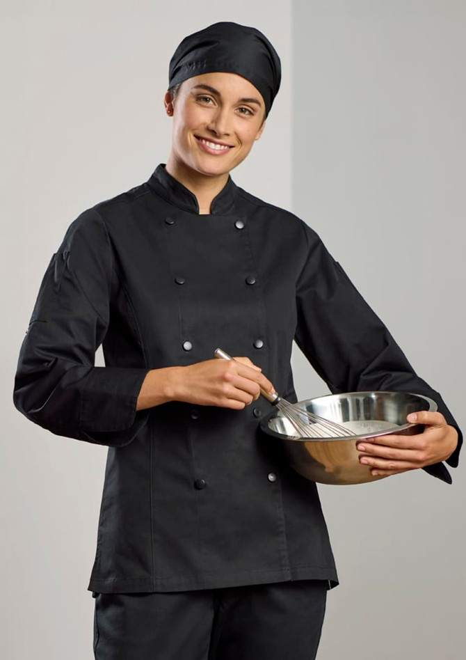 A black long sleeve chef jacket worn by a woman, who is holding a mixing bowl and whisk. The outfit includes a chef's hat.