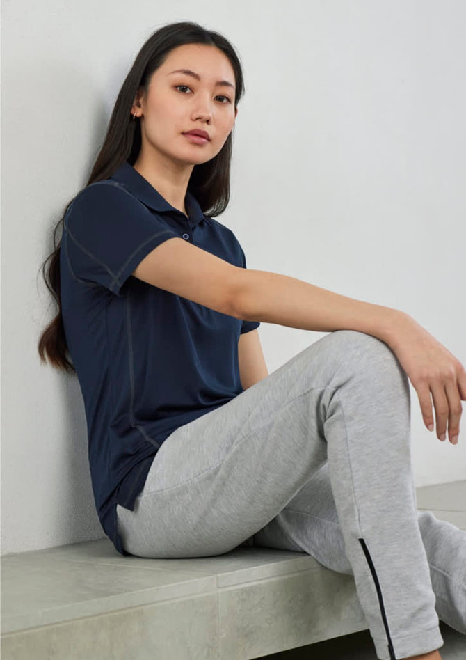 A women's short sleeve polo shirt in navy blue, paired with grey pants, displayed against a plain background.