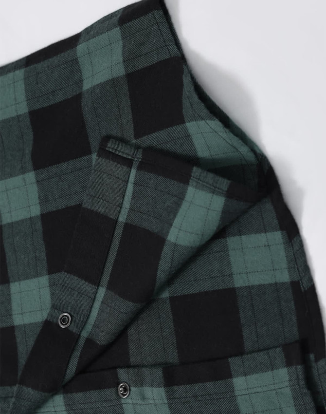 A unisex flannel plaid shirt featuring green and black checks, with buttons and a small pocket detail.