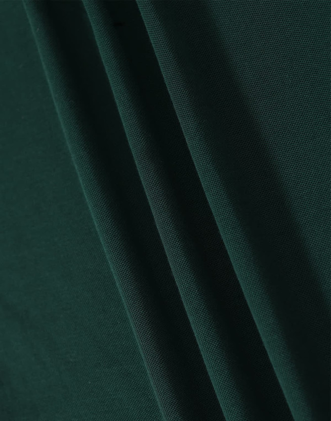A close-up image of dark green fabric with soft texture, showcasing folds and draping.
