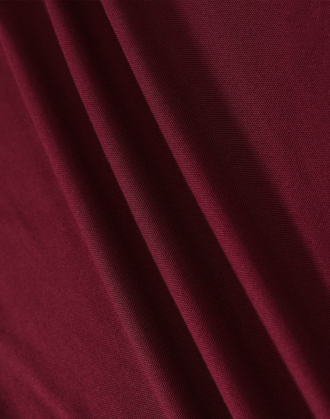 A close-up of a textured fabric in a rich burgundy colour, showcasing its drape and weave.