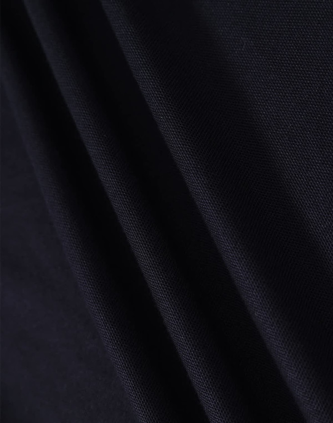 A close-up view of dark navy fabric showcasing its texture and drape. The material appears smooth and woven.