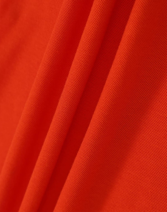 An orange fabric with a textured surface, showcasing the material of the Ladies' Truedry Pique Polo.