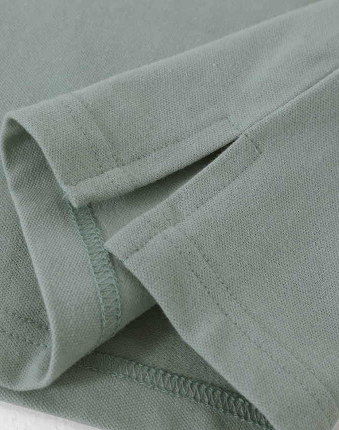A close-up view of a light green men's cotton stretch polo shirt, highlighting the fabric and stitching details.