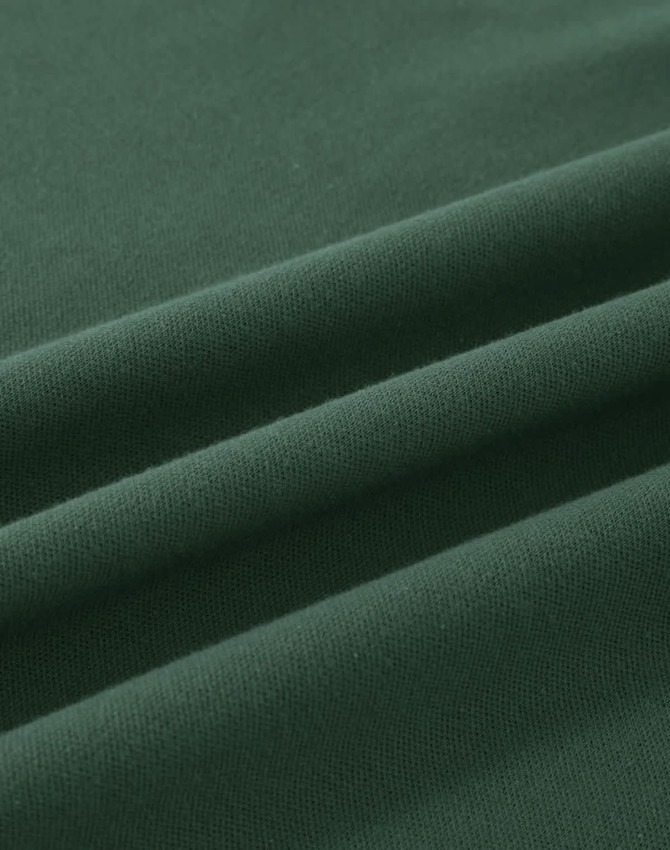 A close-up view of soft, dark green cotton fabric, featuring gentle folds and a smooth texture.