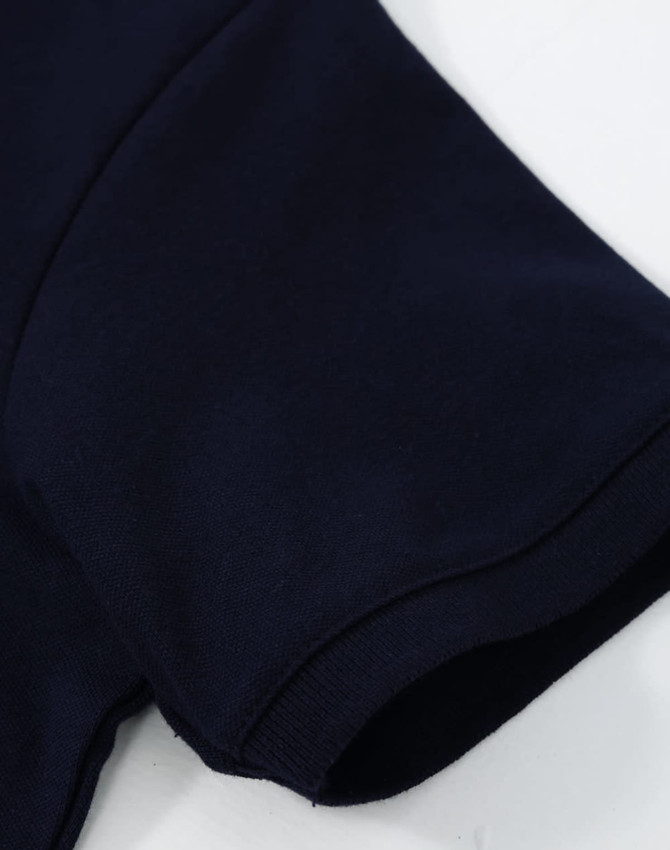 A navy blue ladies cotton stretch polo with a close-up view of the sleeve. It features a logo.