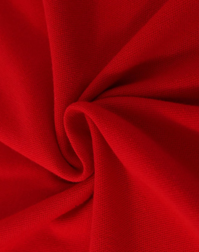 A close-up view of red cotton fabric, showcasing its soft texture and stretch quality. The fabric is smooth and pliable.