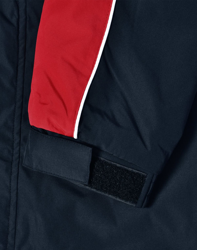 A unisex jacket featuring a navy body with red and white accents and a Velcro fastening on the sleeve.