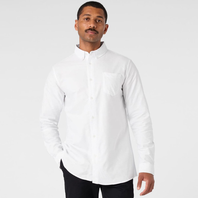 A white button-up Oxford shirt with a collar and a chest pocket, worn by a model. The shirt features a logo.