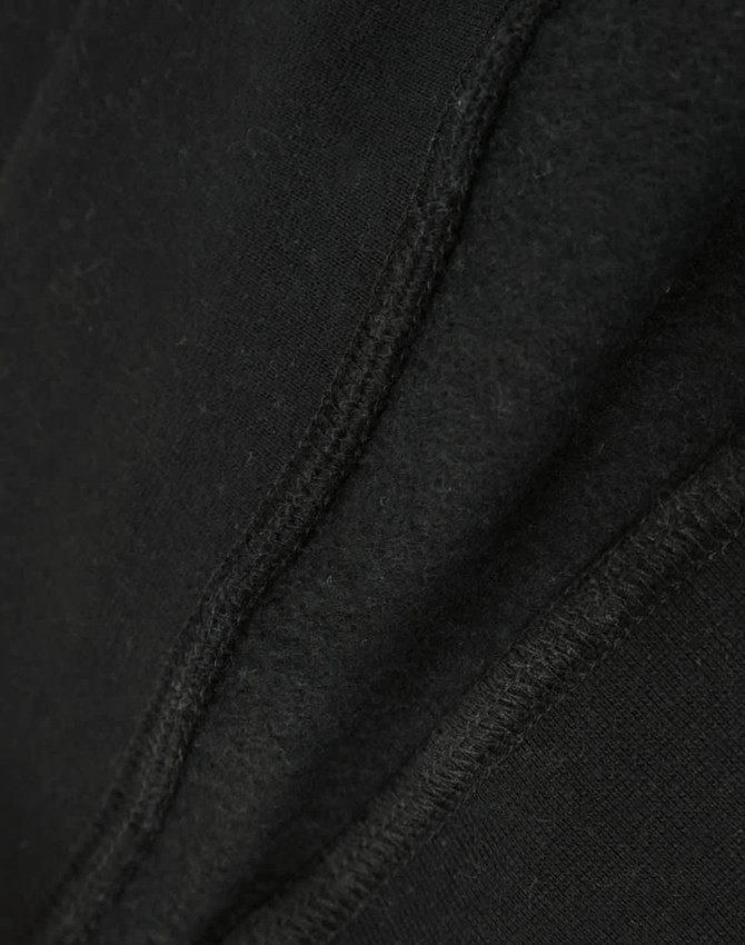 A close-up view of a black crew fleece sweat, highlighting its textured fabric and stitching details.