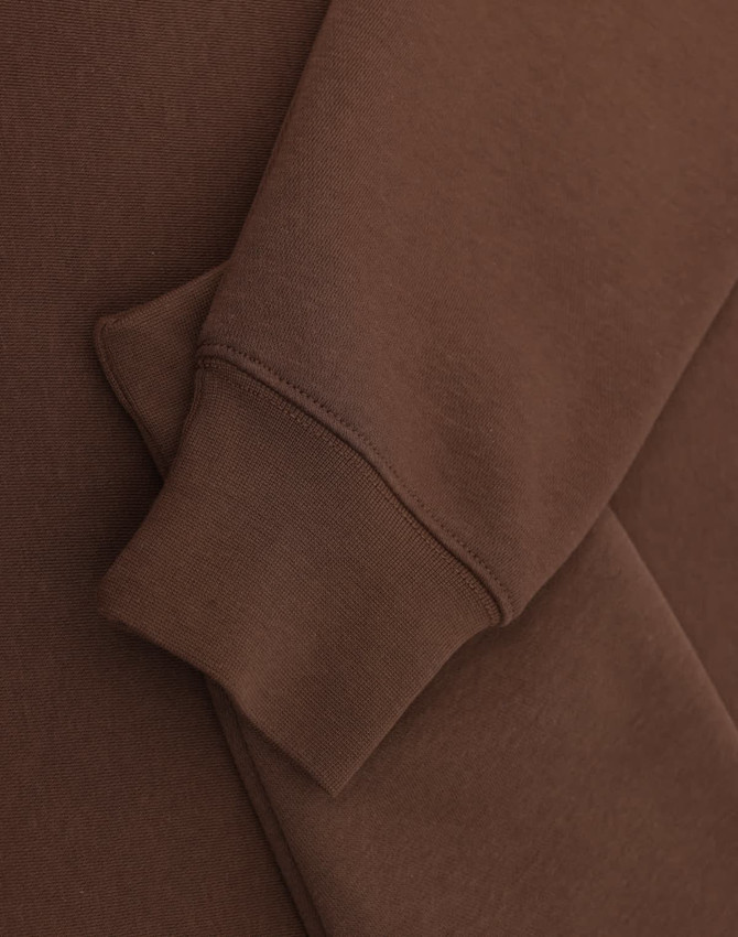 A brown 1/2 zip collar fleecy sweat featuring a smooth fabric and a cuffed sleeve. Includes branding.