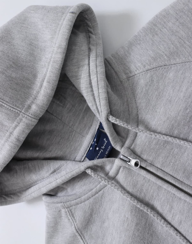 A grey full-zip fleecy hoodie featuring a hood and stitched detailing, with branding visible inside.