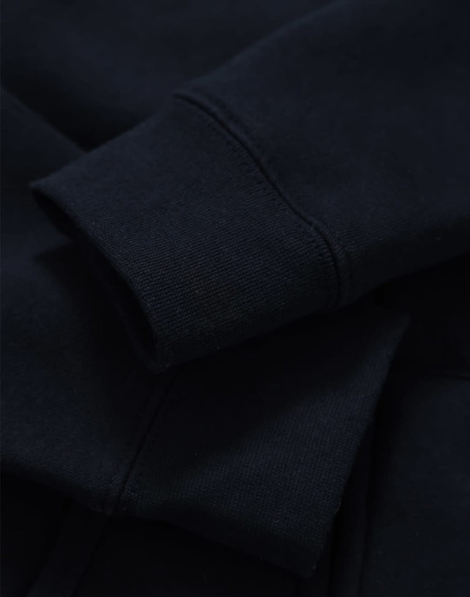 A close-up of a navy full-zip fleecy hoodie showcasing the cuffs and fabric texture. It has a logo.