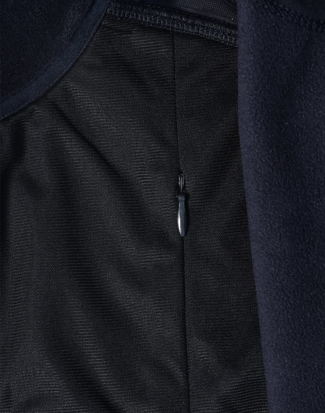 A close-up of a navy blue softshell jacket, featuring a zippered pocket and textured fabric.