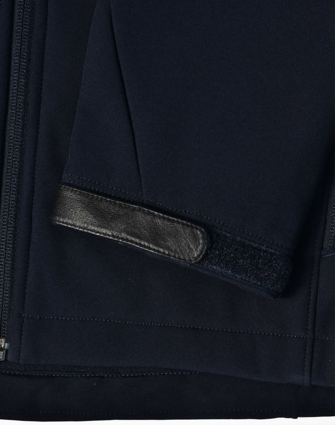A navy softshell jacket featuring a sleek design with a leather patch on the sleeve. Includes a logo.