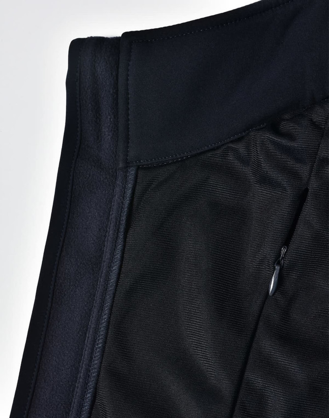 A close-up of a black ladies' softshell hi-tech vest showcasing its fabric textures and a zippered pocket.