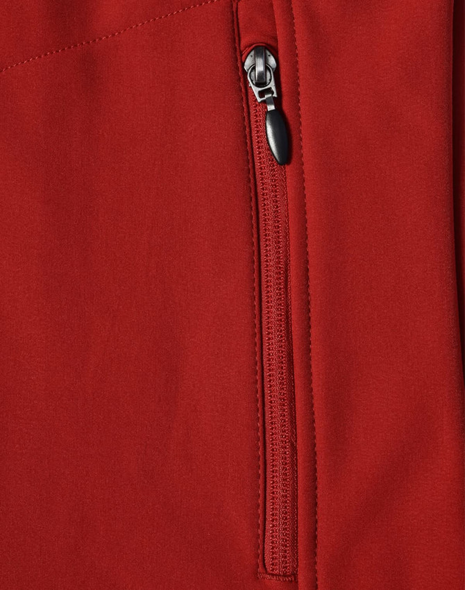 A close-up of a red softshell vest featuring a zippered pocket and a logo.