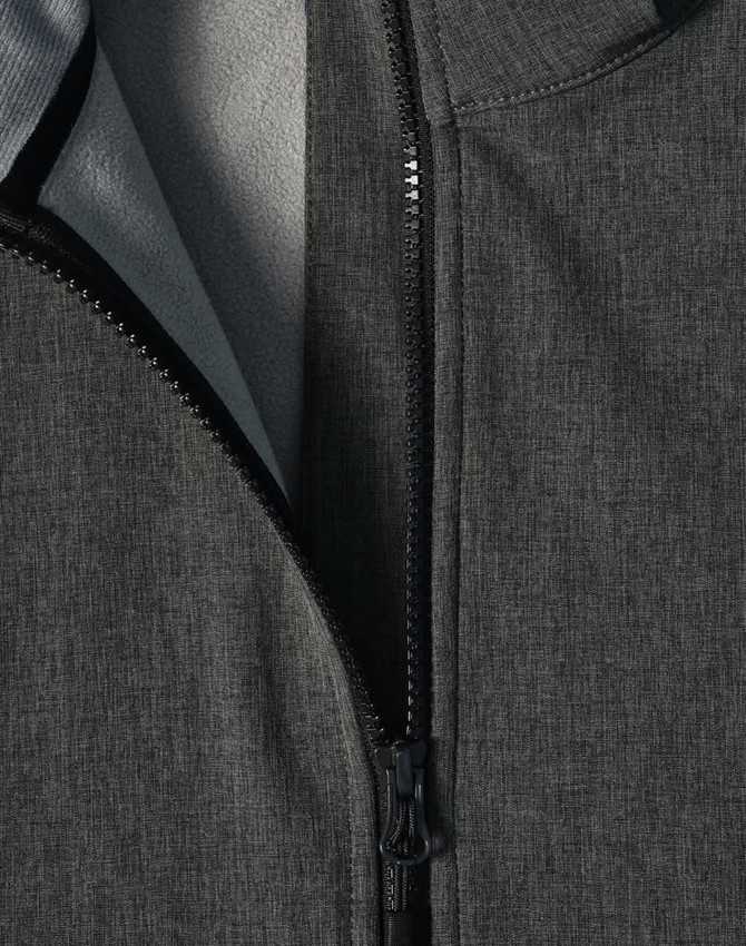 A close-up of a grey softshell full zip hoodie featuring a zipper and a soft inner lining. It includes a logo.