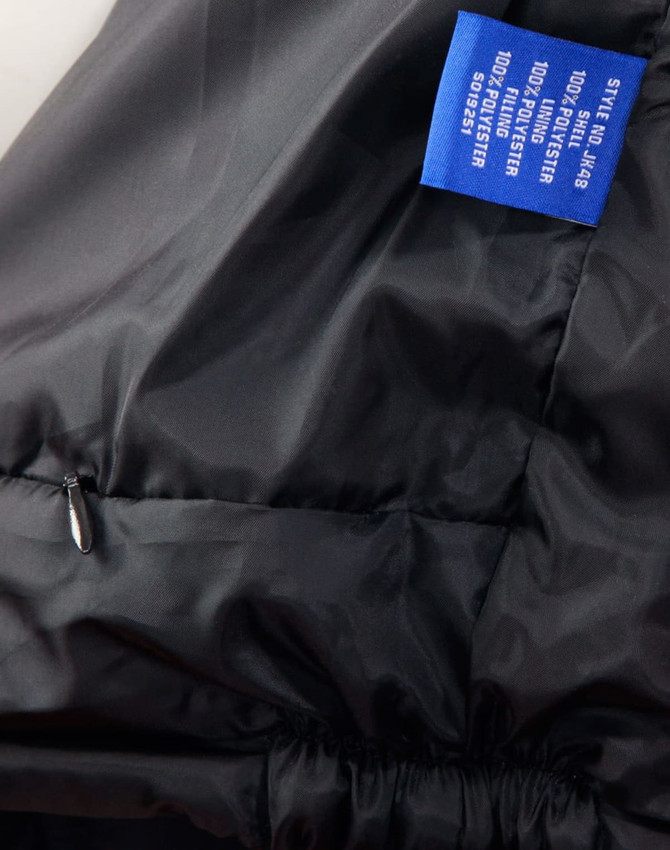 A black heavy quilted jacket featuring a zippered pocket and a label with branding.