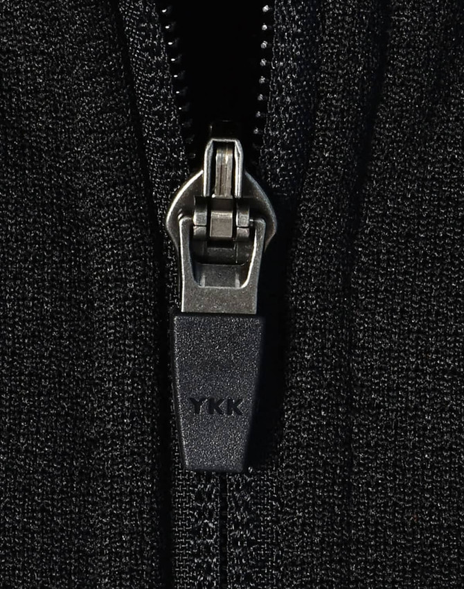 A close-up of a black zip on a fleece jacket featuring a YKK zipper. The fabric appears textured and soft.