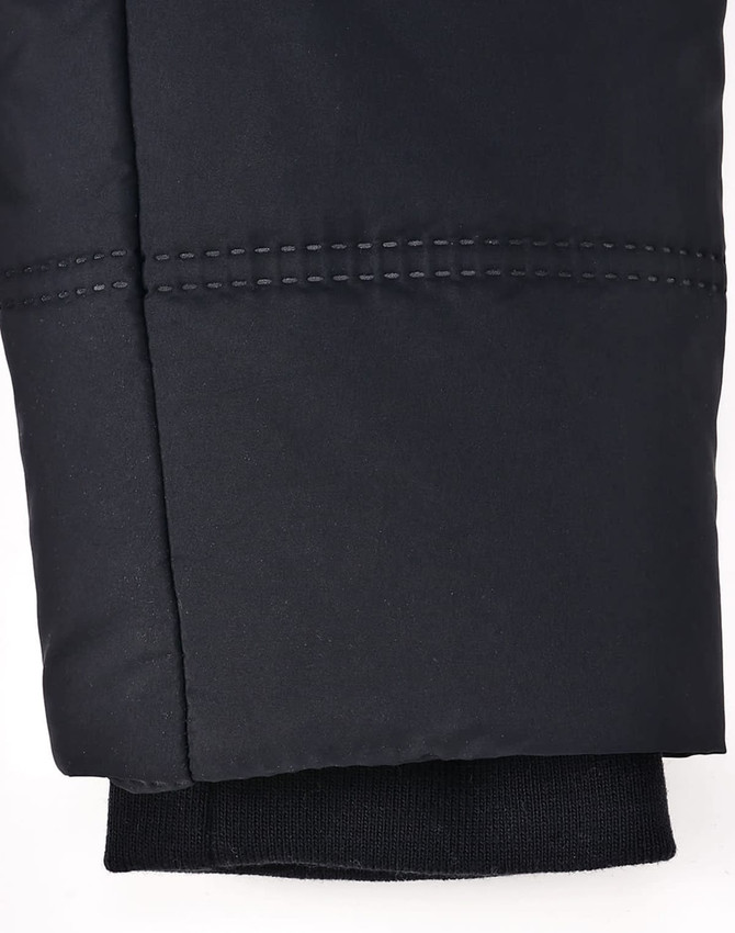 A close-up of a black seamless parka jacket sleeve, featuring stitching details and a knitted cuff.
